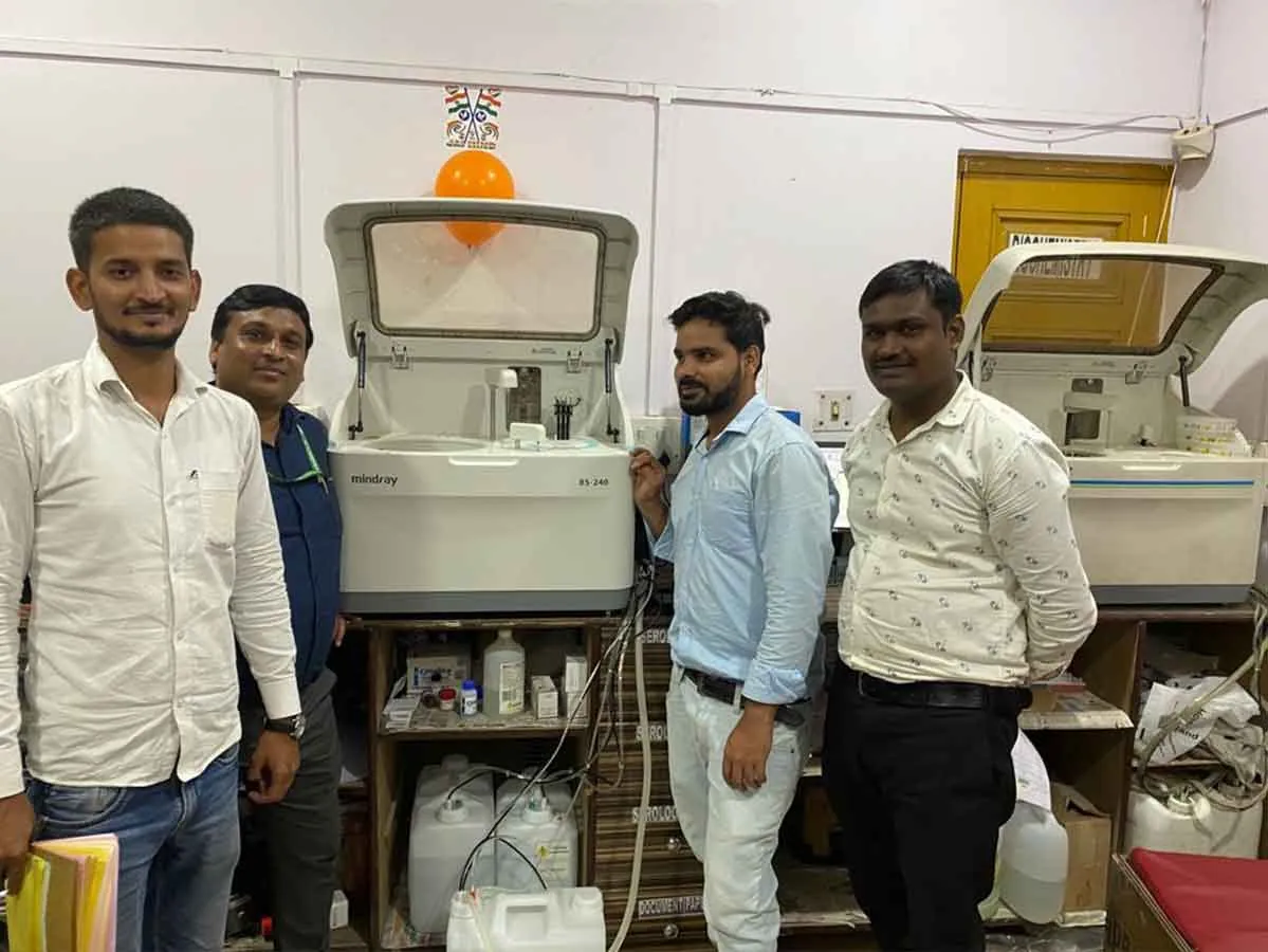 An installation team standing beside two clinical chemistry analysers